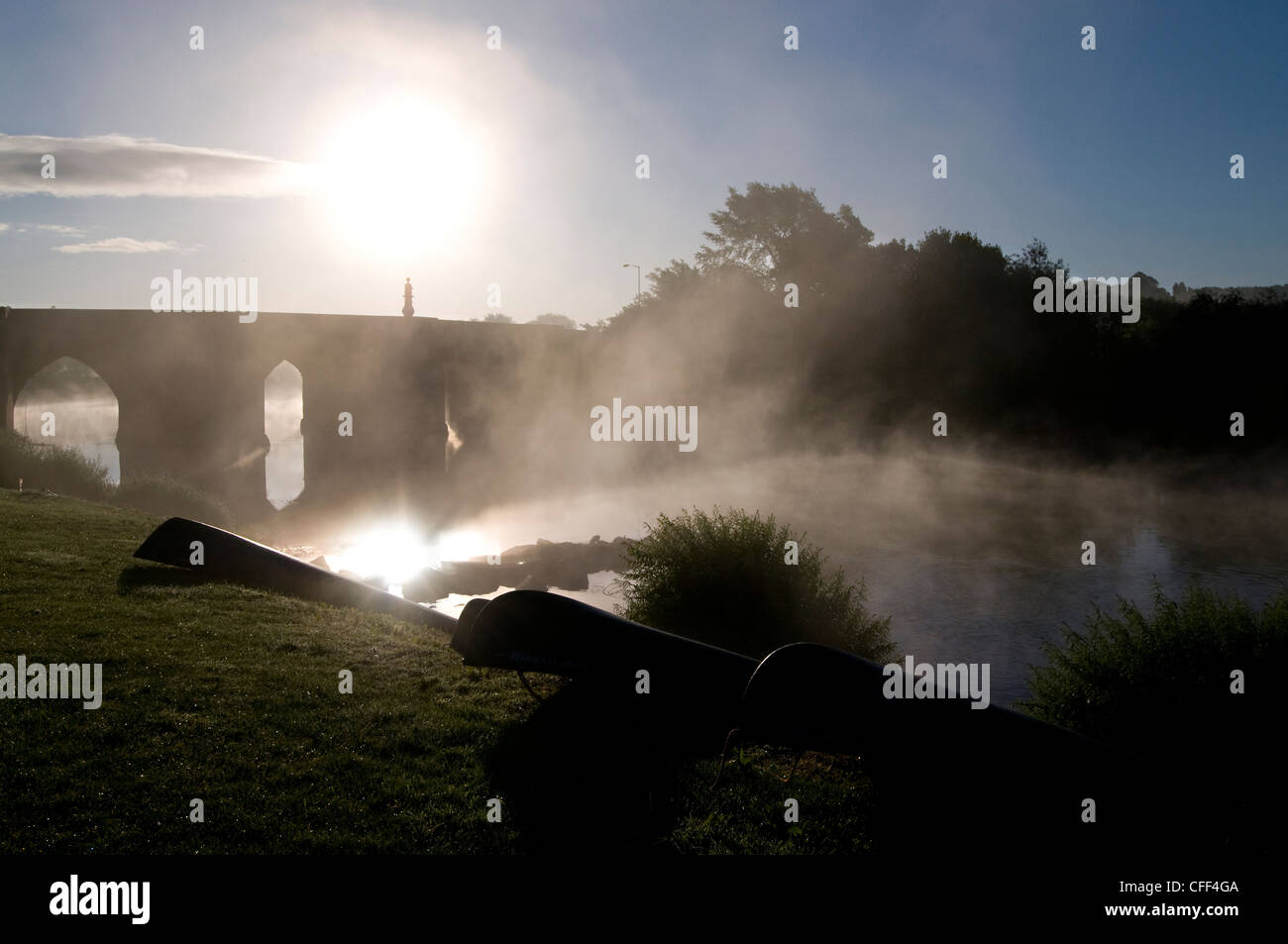 Canoes laying on the river bank as the early morning mist raises from the river Wye at Ross-on-Wye, Herefordshire,Britain Stock Photo