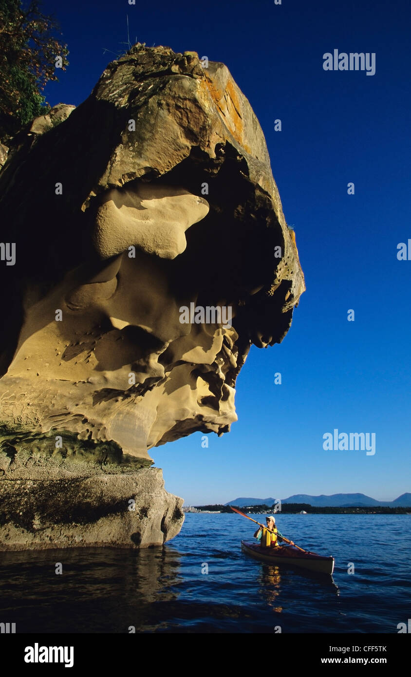 A woman kayaking past salterosion formed sandstone, Gabriola Island