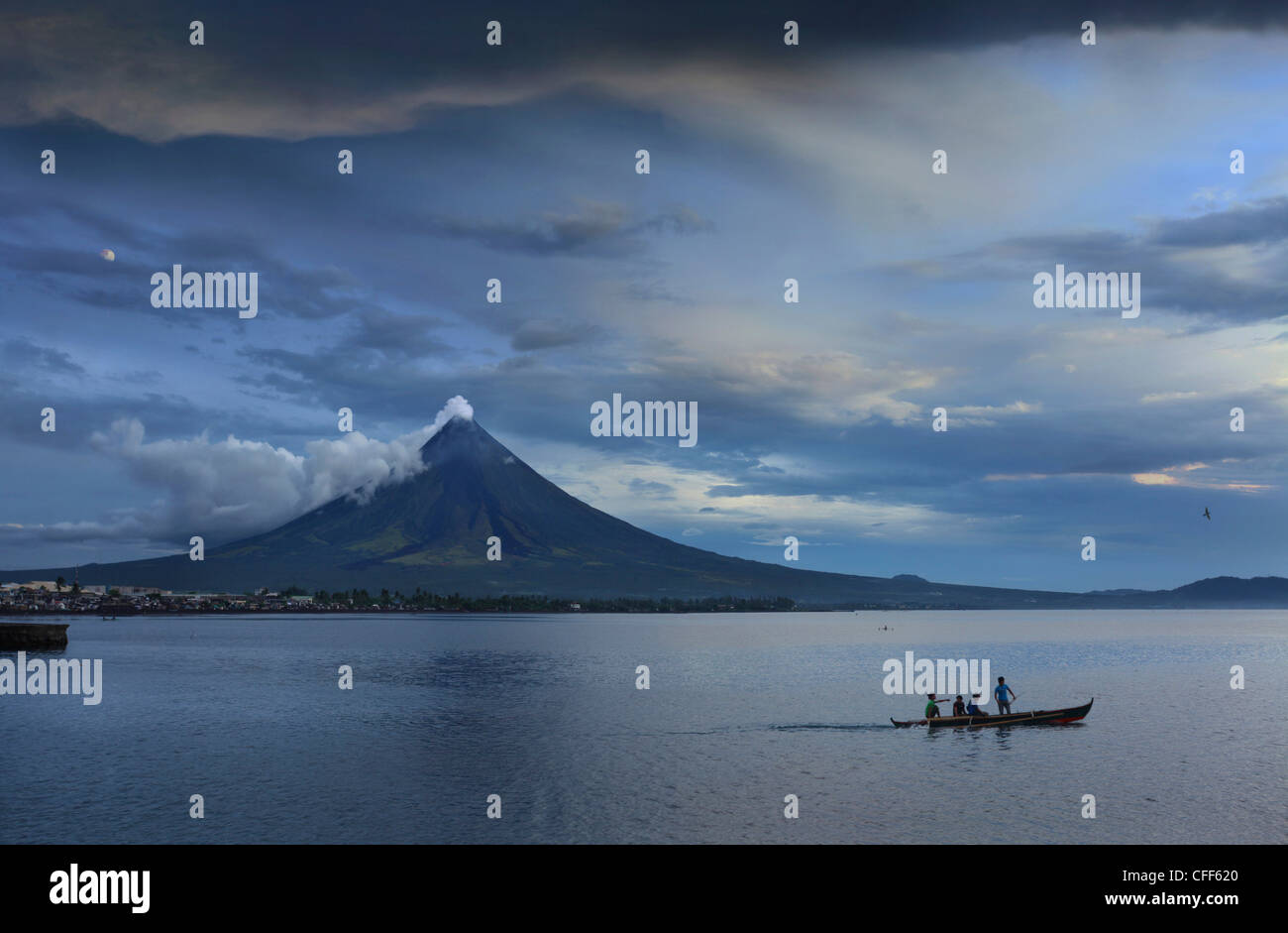 Young people on outrigger with steaming Mayon Volcano, Legazpi City, Luzon Island, Philippines, Asia Stock Photo