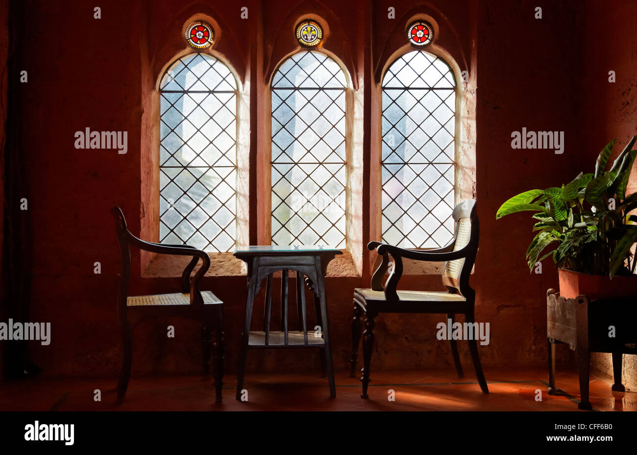 Set of captains chairs with a coffee table at an arched leaded window Stock Photo