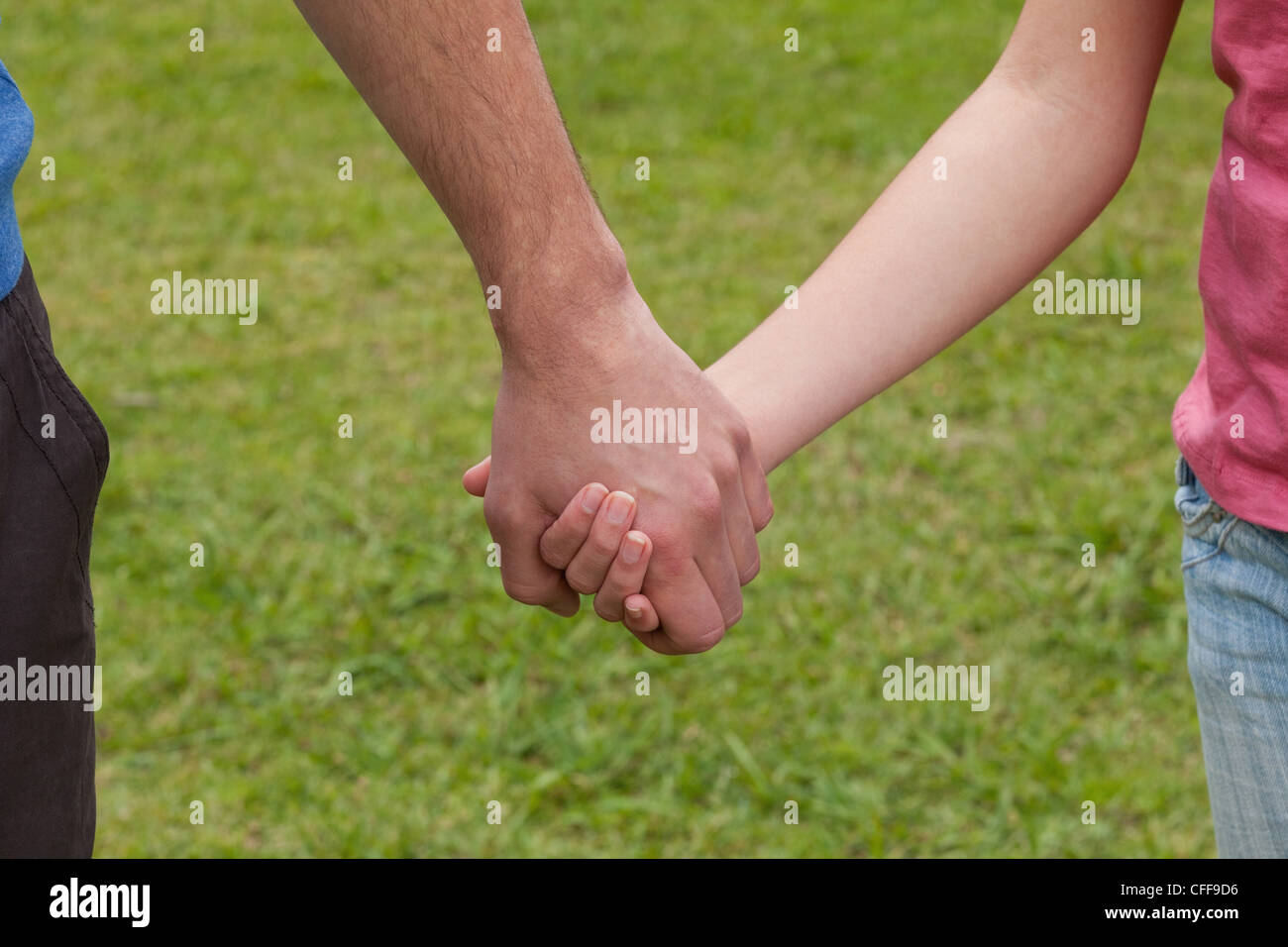 Young couple holding their hands in a park Stock Photo - Alamy