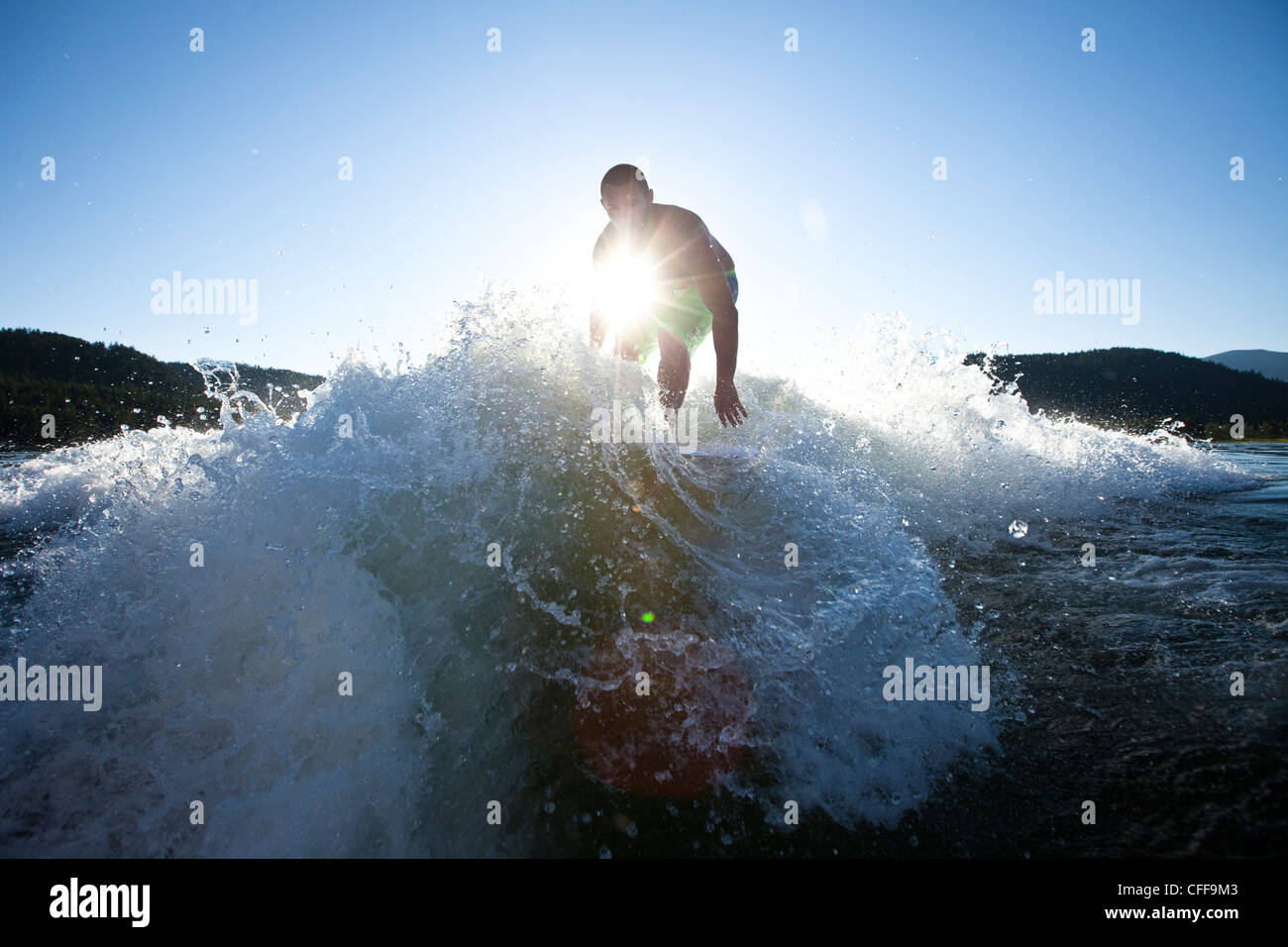 A athletic male surfing behind a wakeboard boat at sunset in Idaho