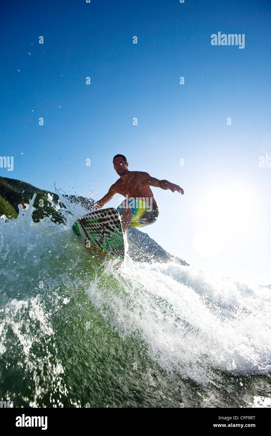 A athletic male surfing behind a wakeboard boat on a lake in Idaho. Stock Photo