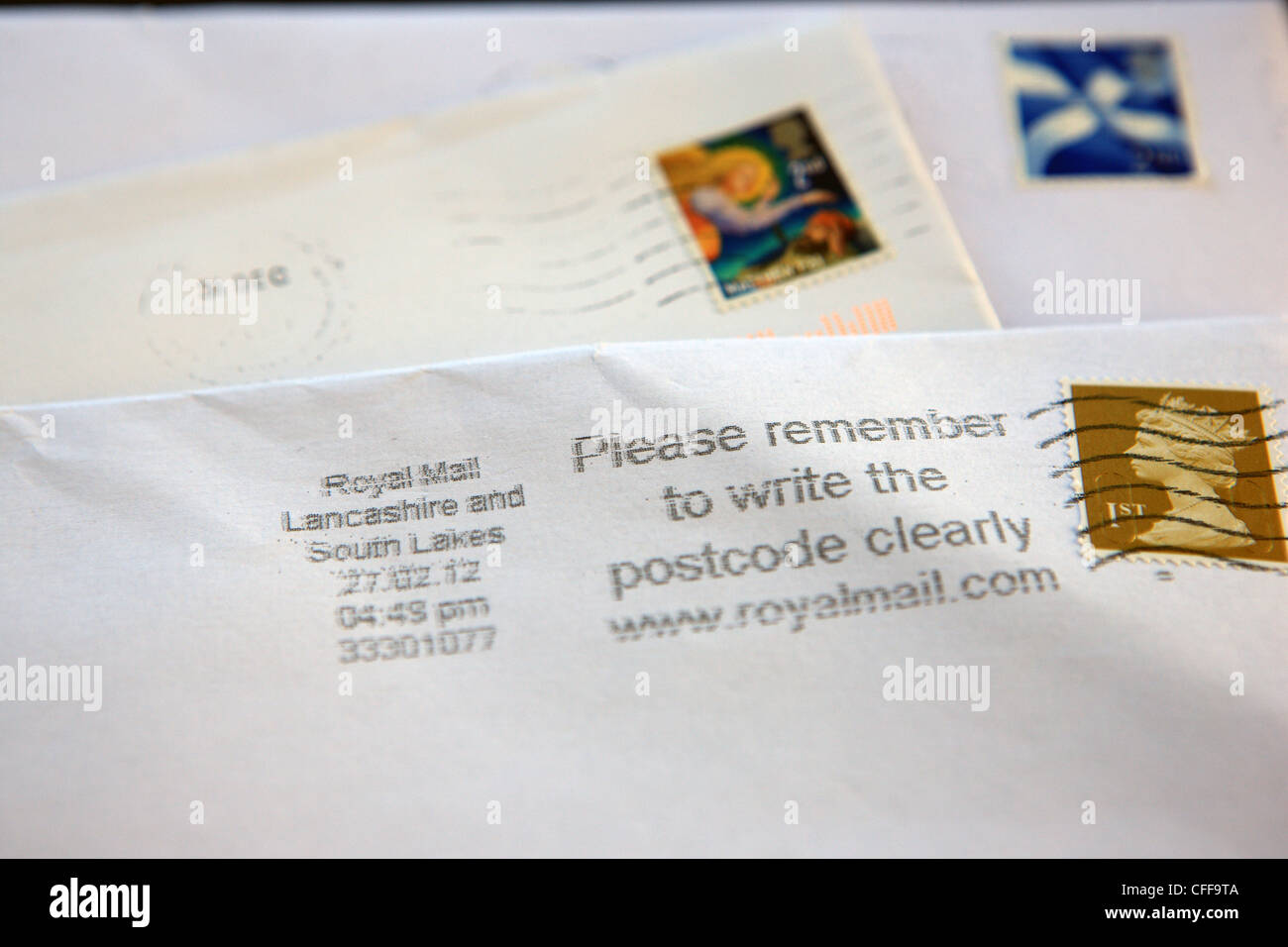 British stamps on envelopes with postcode reminder message by Royal