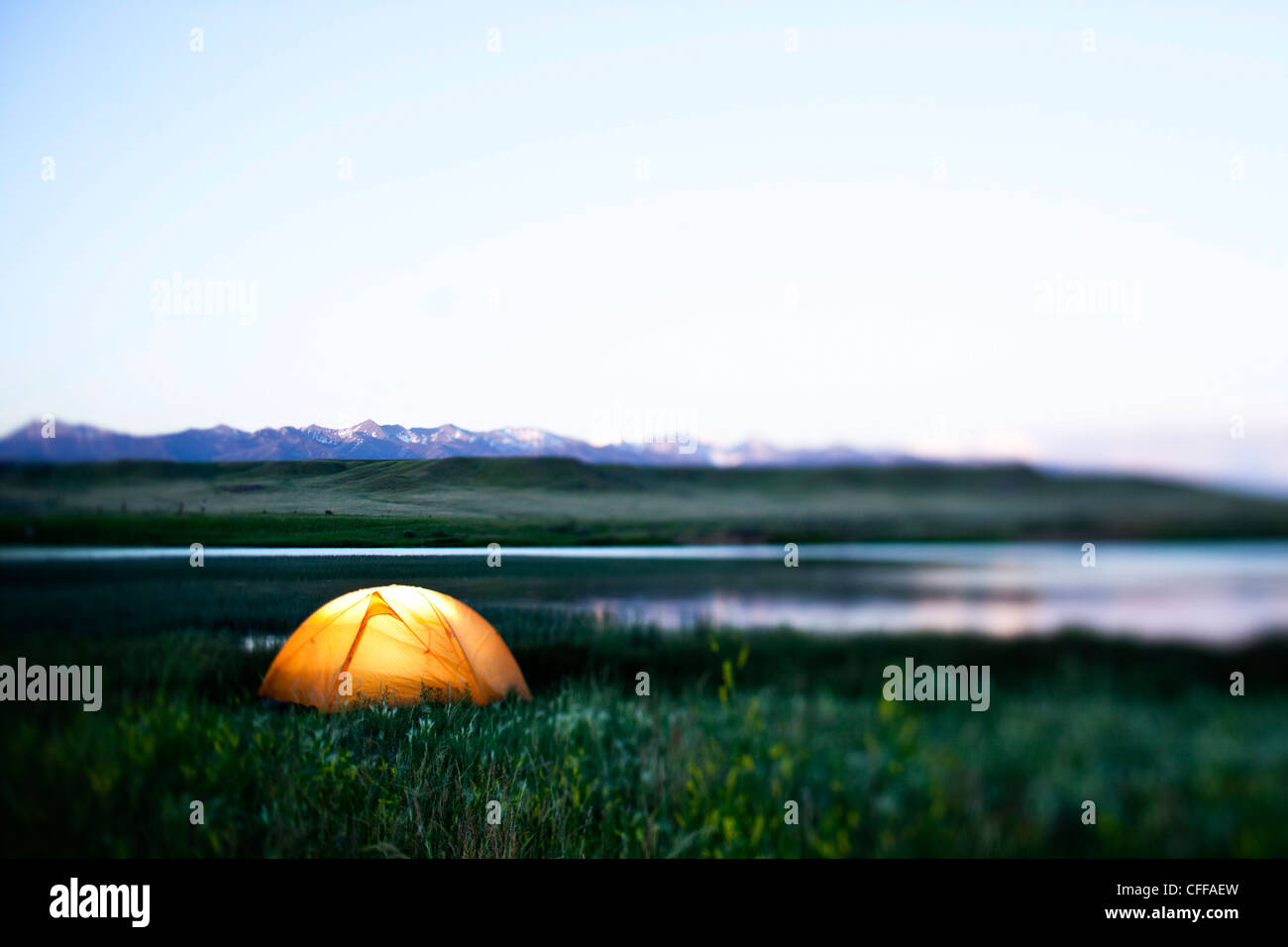 A glowing tent next to a lake at sunset in Montana. Stock Photo