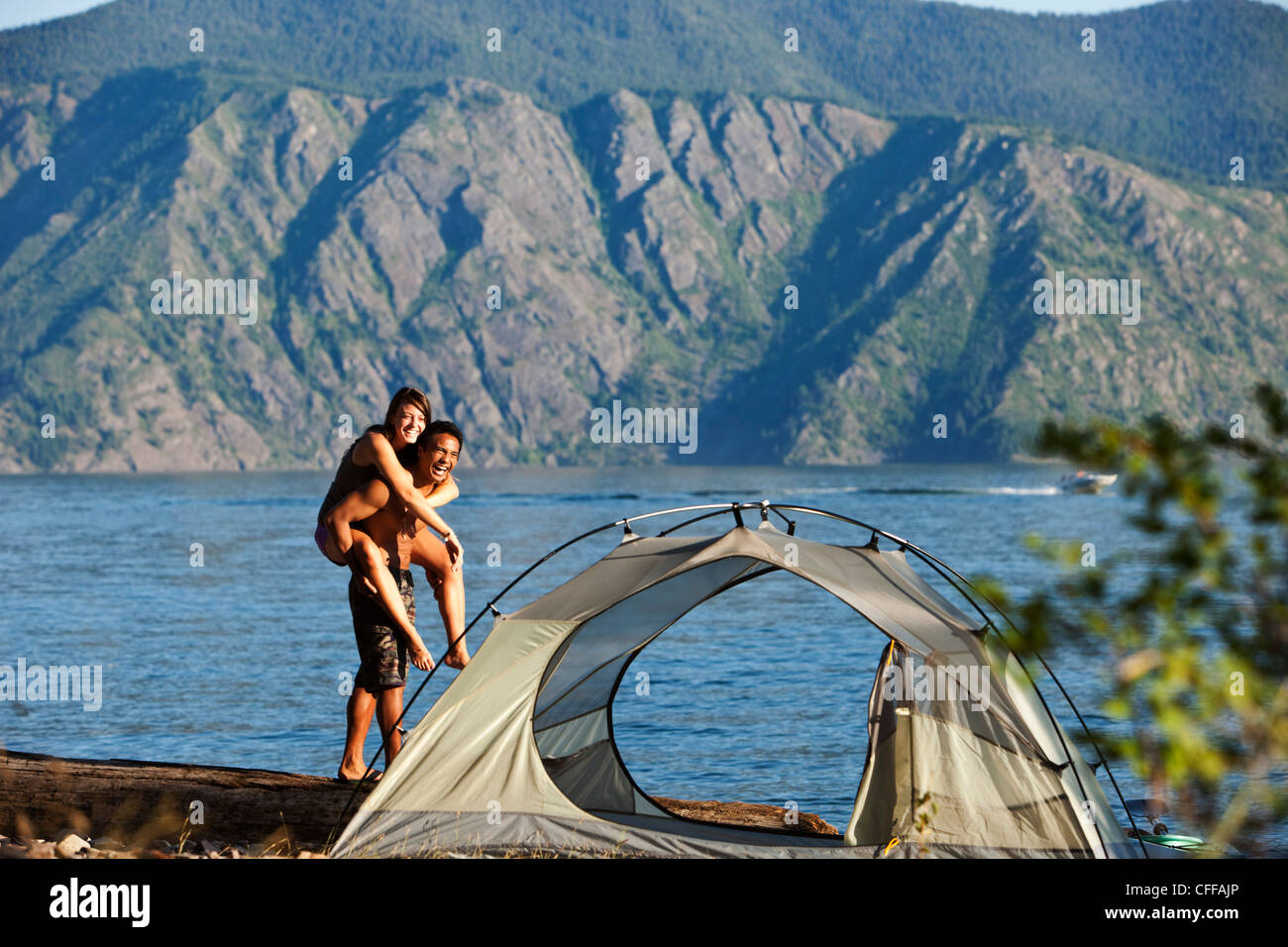 A happy young adult couple smile and laugh on a camping trip next to a lake in Idaho. Stock Photo