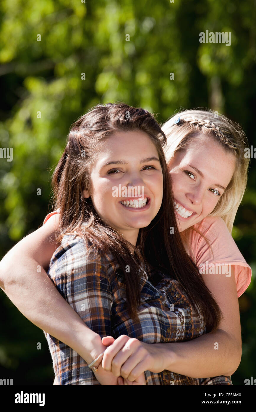Young smiling woman wrapping her arms around her best friend Stock