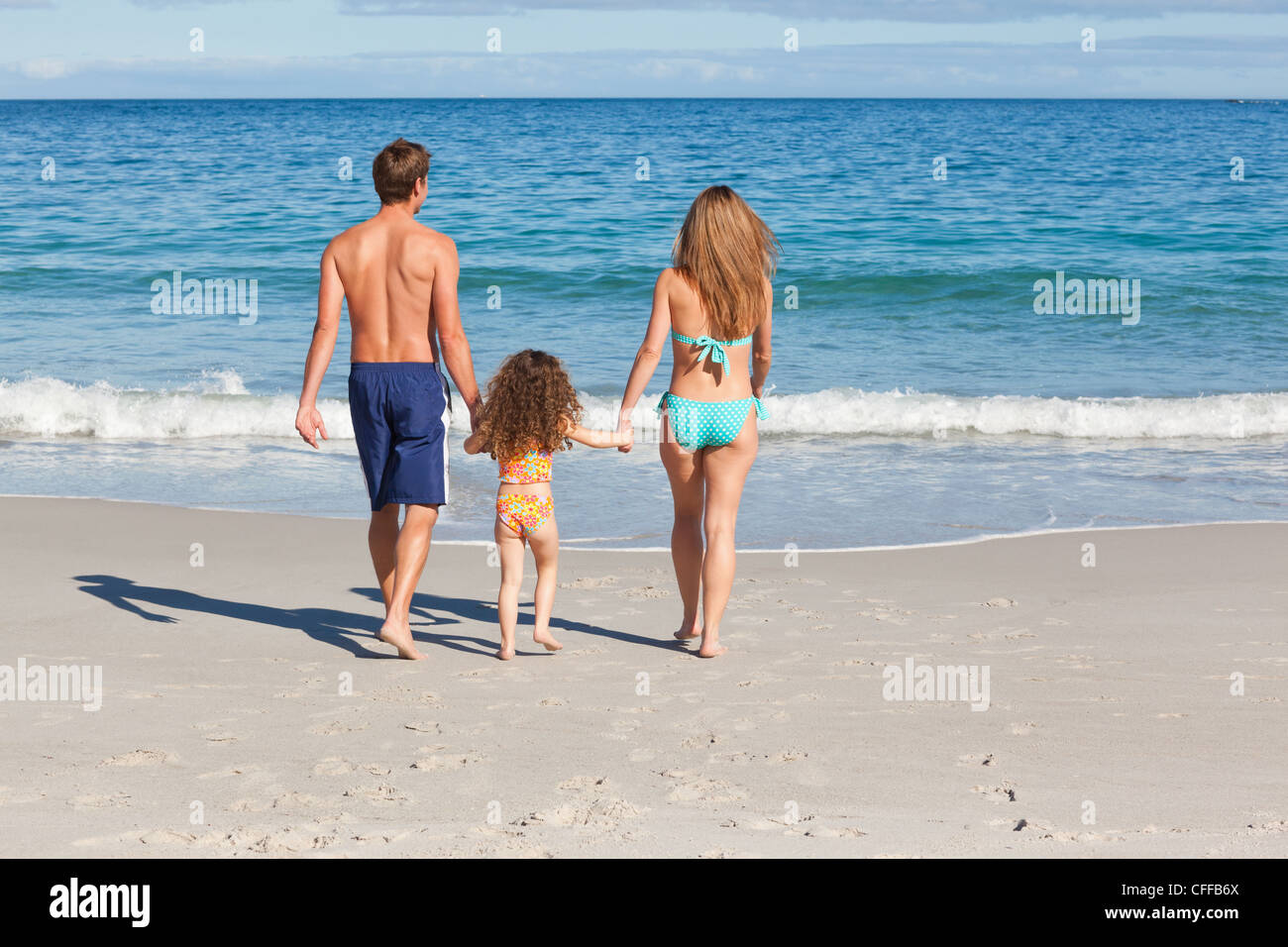 Family on the beach walking towards the sea Stock Photo