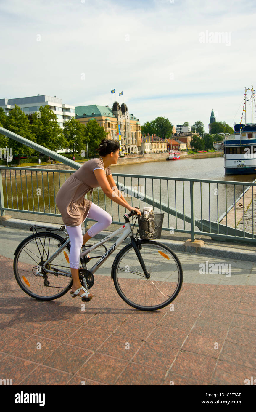 Girl cycling over the Aurasilta bridge Turku Finland with the Town Hall on left and Cathedral spire on the skyline Stock Photo