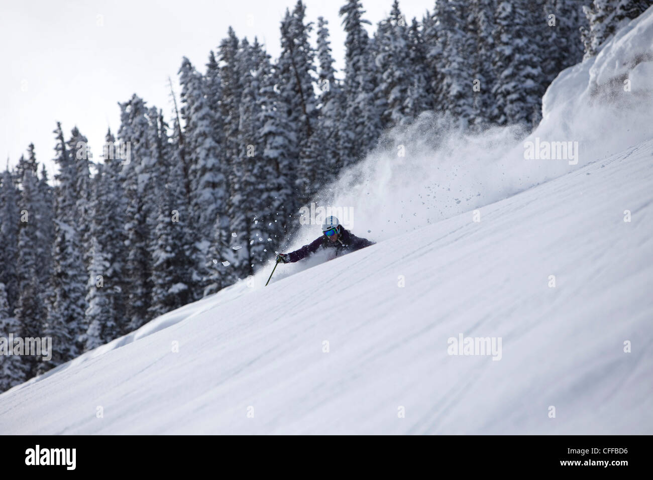 A athletic skier rips fresh deep powder turns in the backcountry on a stormy day in Colorado. Stock Photo