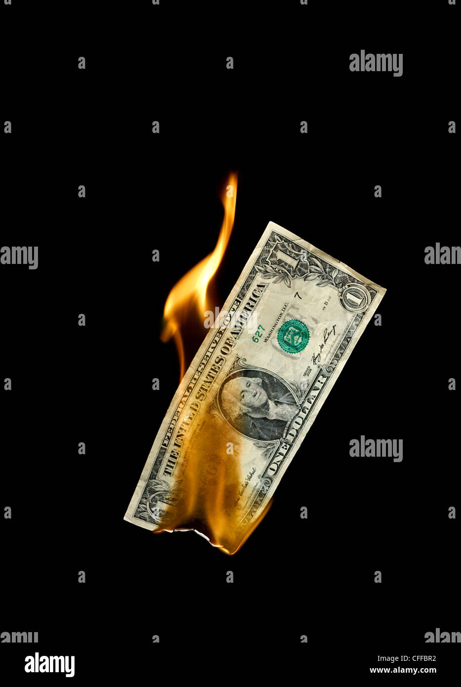 A burning dollar bill symbolizing careless money management and the phrase money to burn Stock Photo