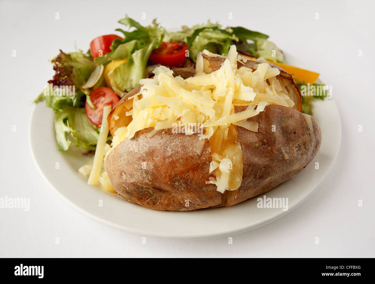 A Cheddar cheese baked potato on a plate with side salad Stock Photo