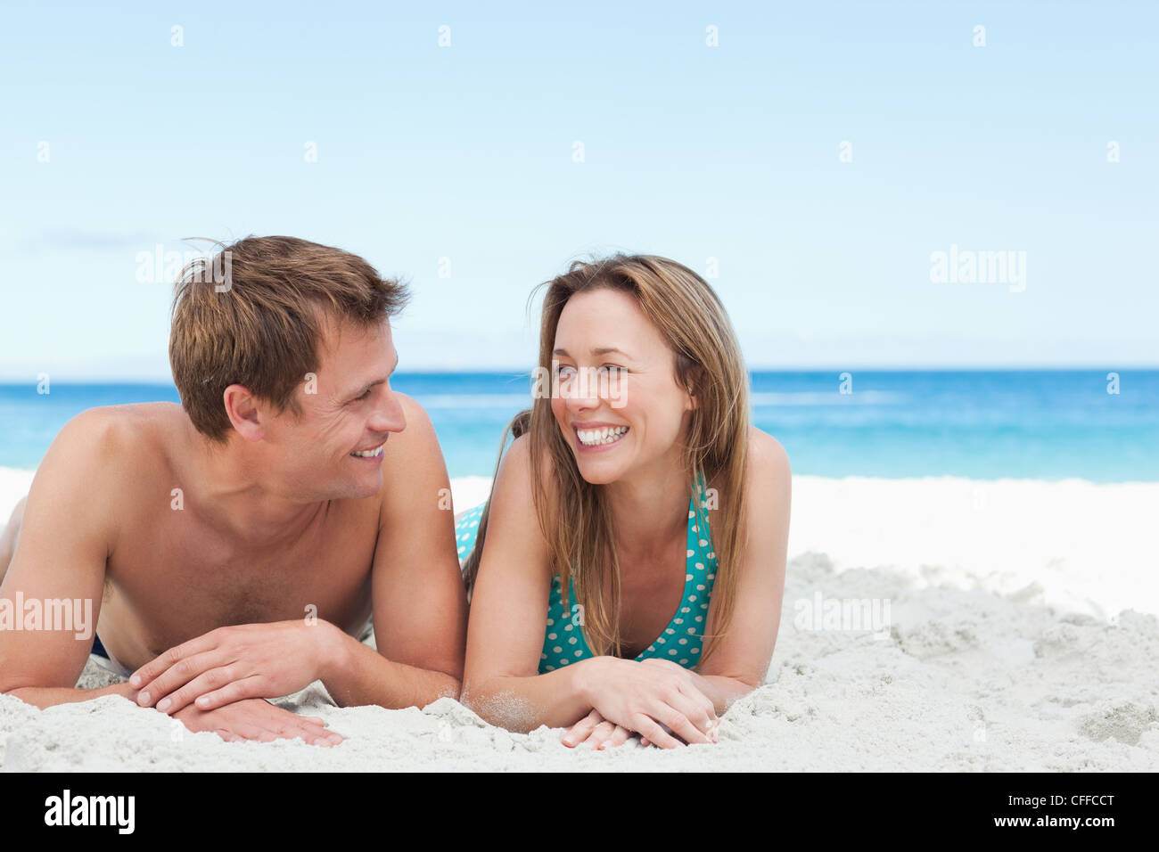Happy couple lying on the beach together Stock Photo - Alamy