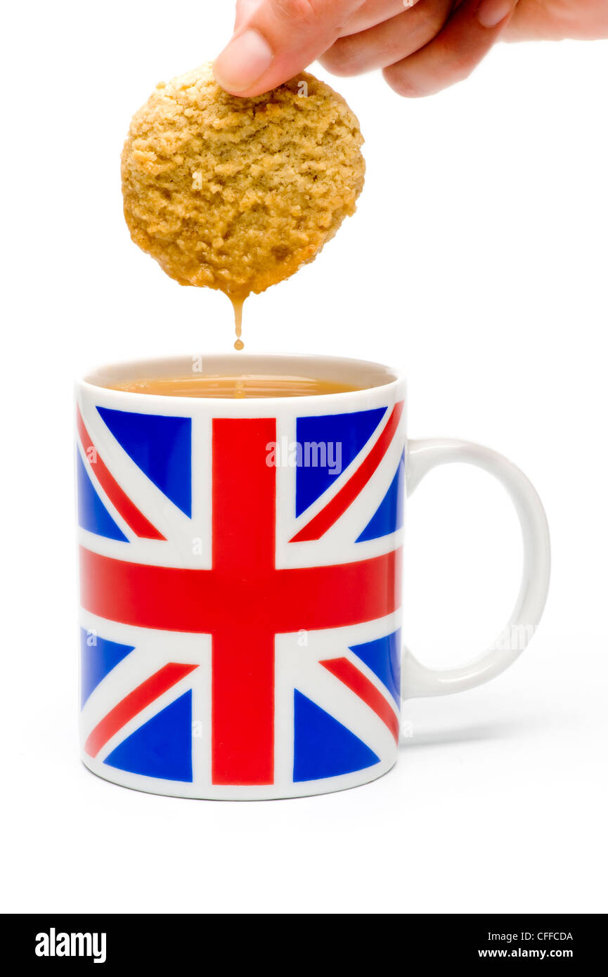 Biscuit dunking in mug of tea shot in studio on white background. Stock Photo