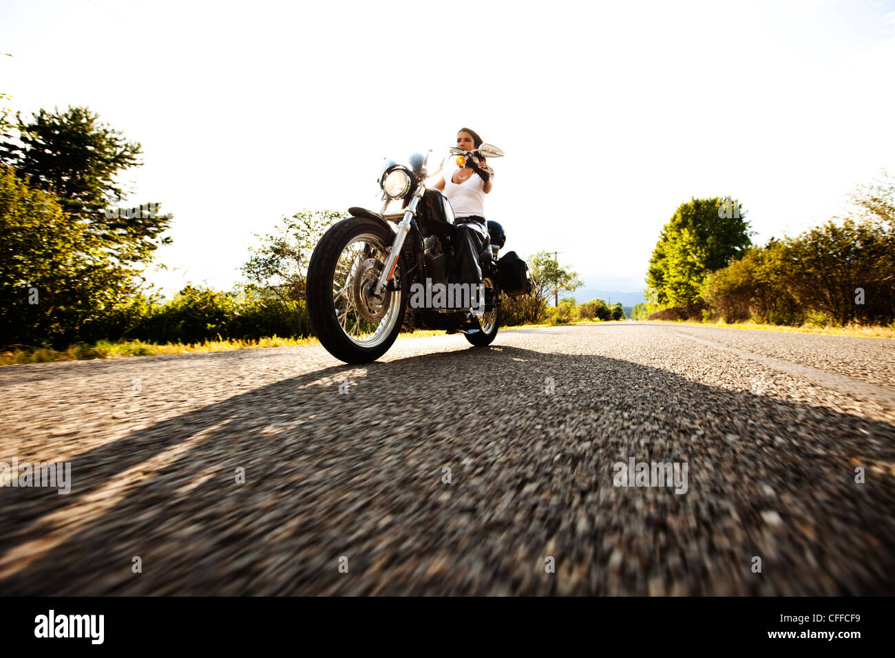 A sexy woman riding her motorcycle on a smooth country road in Idaho. Stock Photo