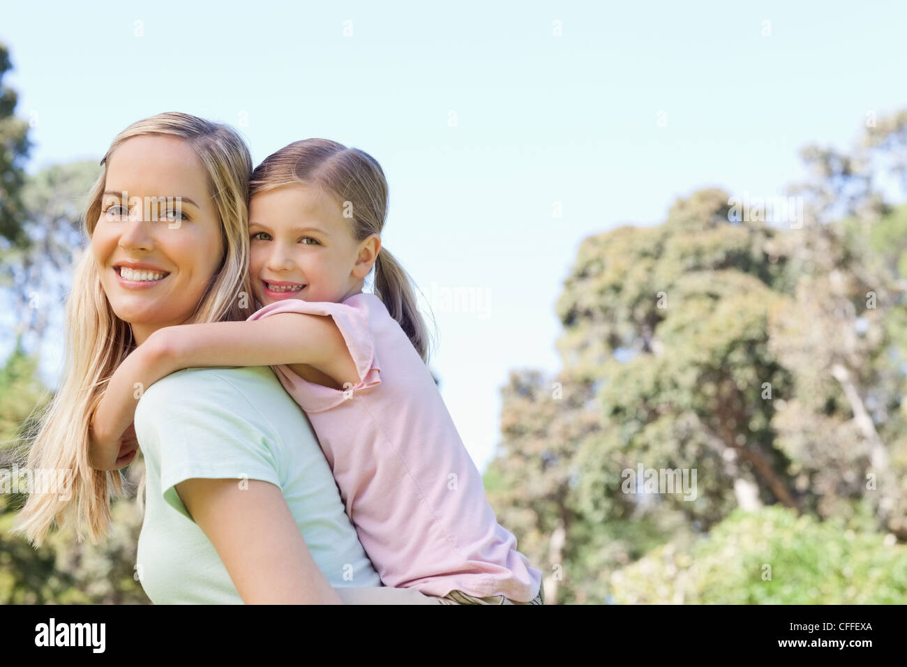 Smiling mother giving her daughter a piggy back Stock Photo