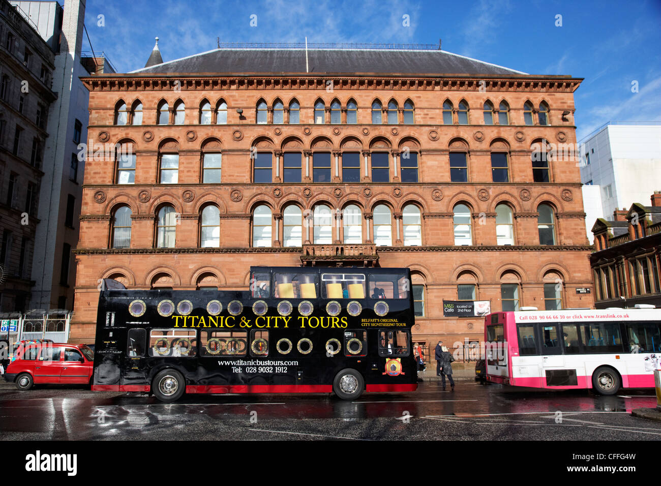 titanic and city open bus tours going past old richardson owden warehouse building donegall square north Belfast city centre Stock Photo