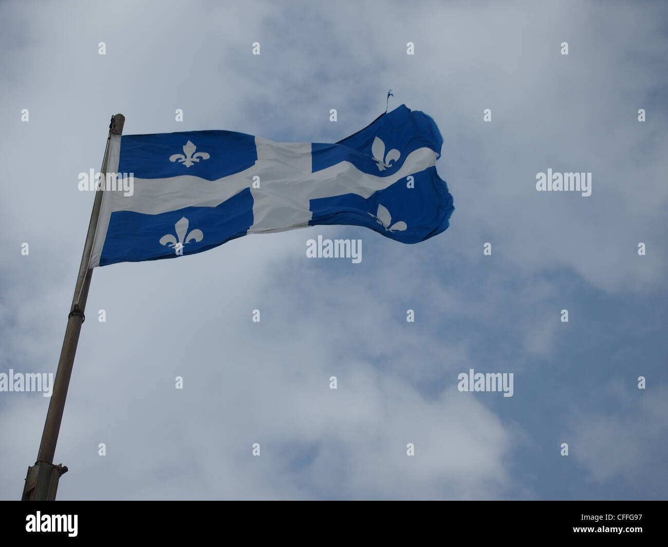 Quebec Fleur de Lys flag waving with cloudy sky in background Stock Photo