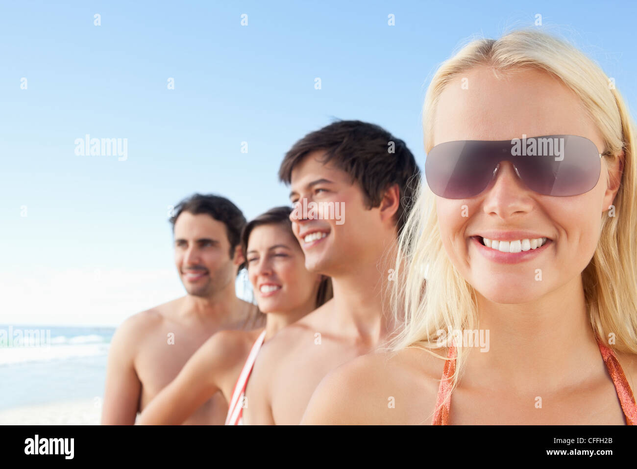 Woman smiling while wearing sunglasses as her friends look to the side Stock Photo