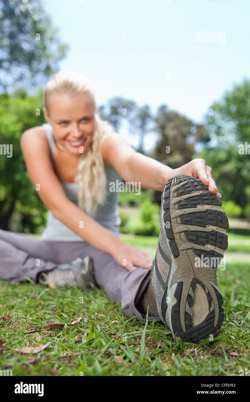 Sportswoman doing her stretches on the lawn Stock Photo