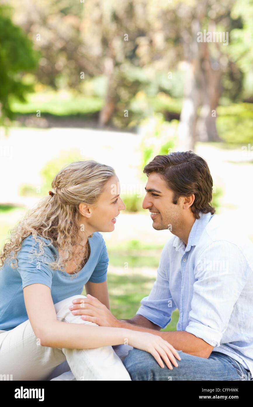 Side view of a happy couple sitting on the lawn Stock Photo - Alamy