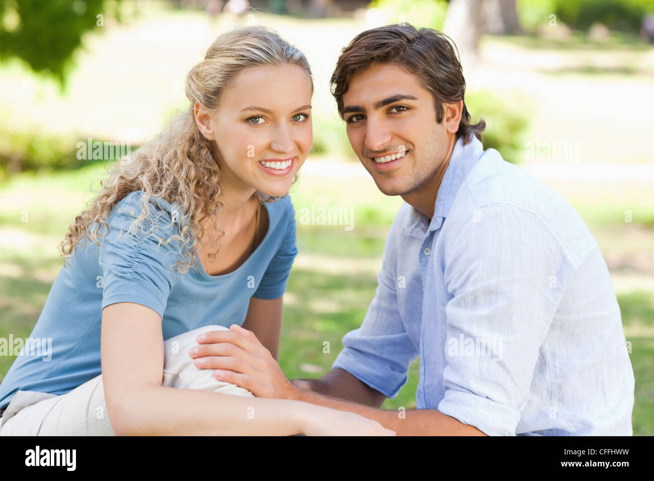 Side view of a happy couple sitting on the grass Stock Photo - Alamy