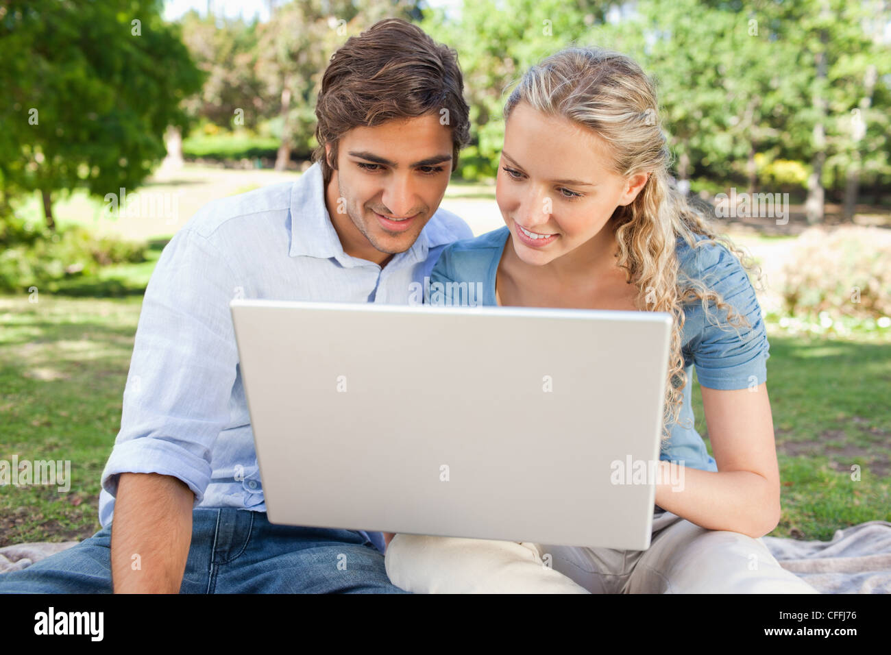 Couple using a laptop in the park Stock Photo - Alamy