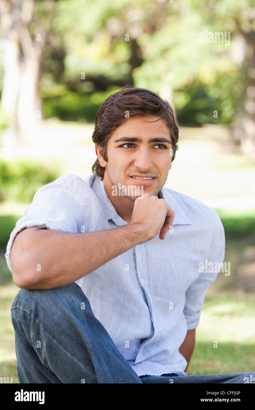 Man thoughtfully sitting on the lawn Stock Photo