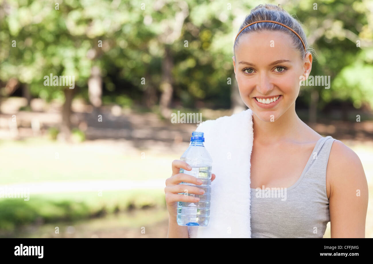 Smiling sportswoman with a towel and a bottle of water Stock Photo - Alamy