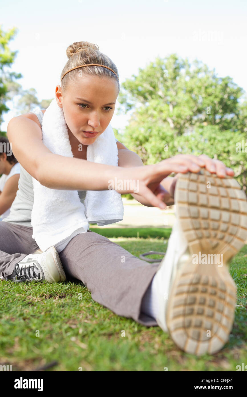 Sportswoman sitting on the lawn while doing her stretches Stock Photo ...