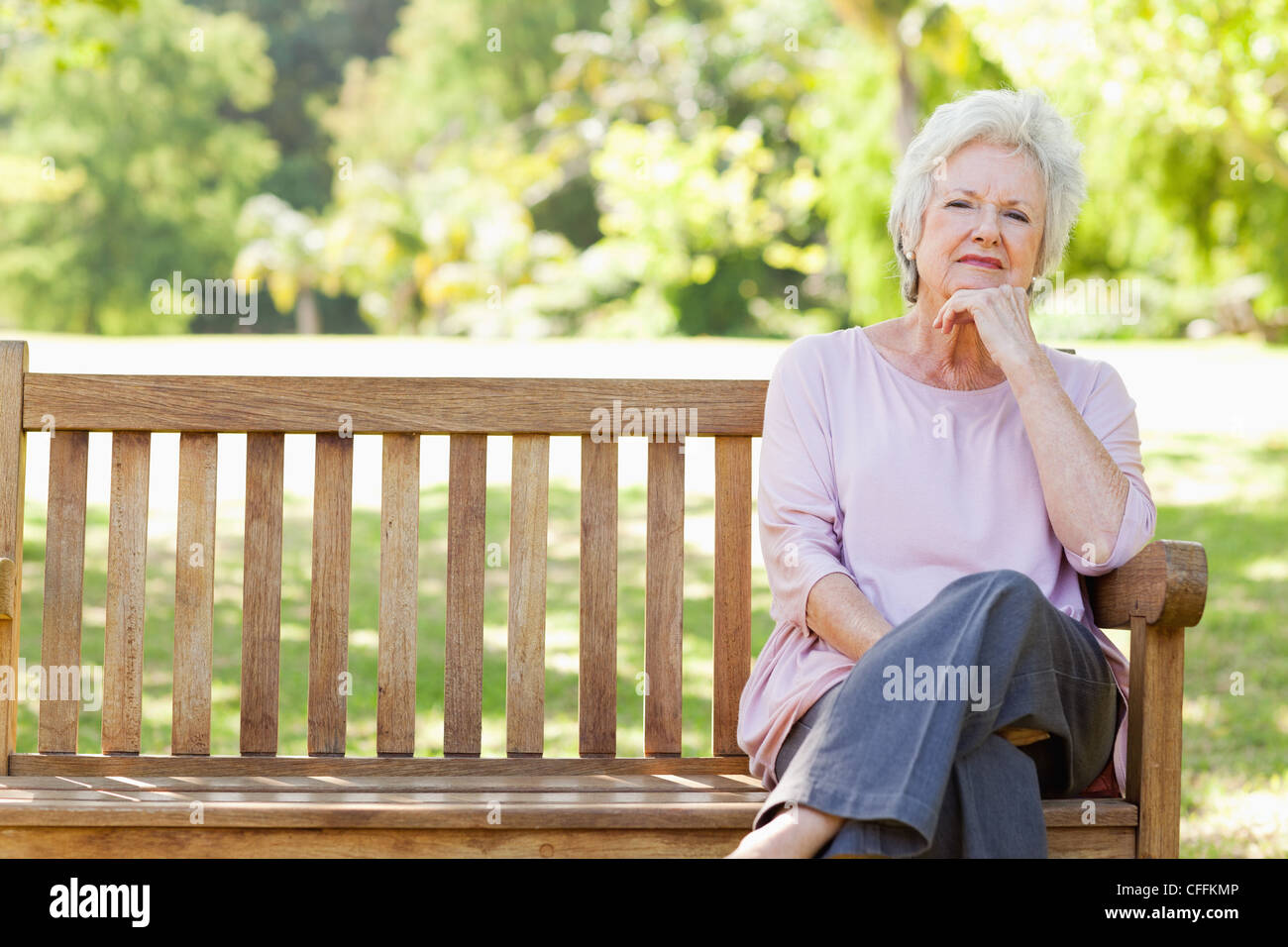 Woman looking ahead thoughtfully while sitting on a bench Stock Photo