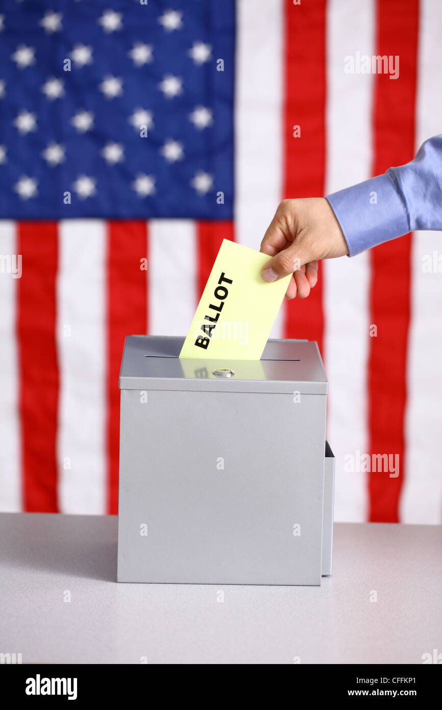 Hand putting ballot into ballot box, voting concept, American flag background Stock Photo