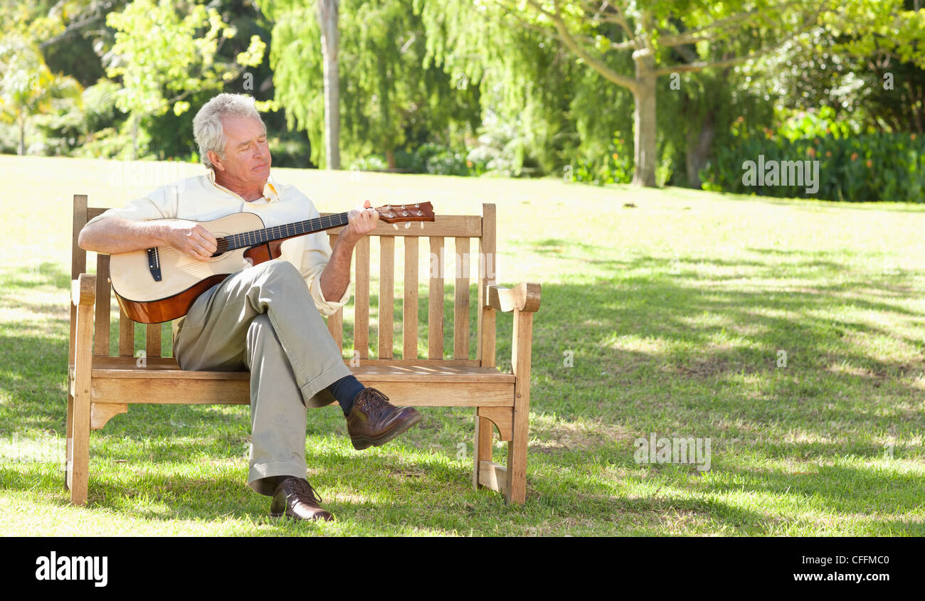 Man playing a guitar as he sits with his legs crossed Stock Photo Alamy