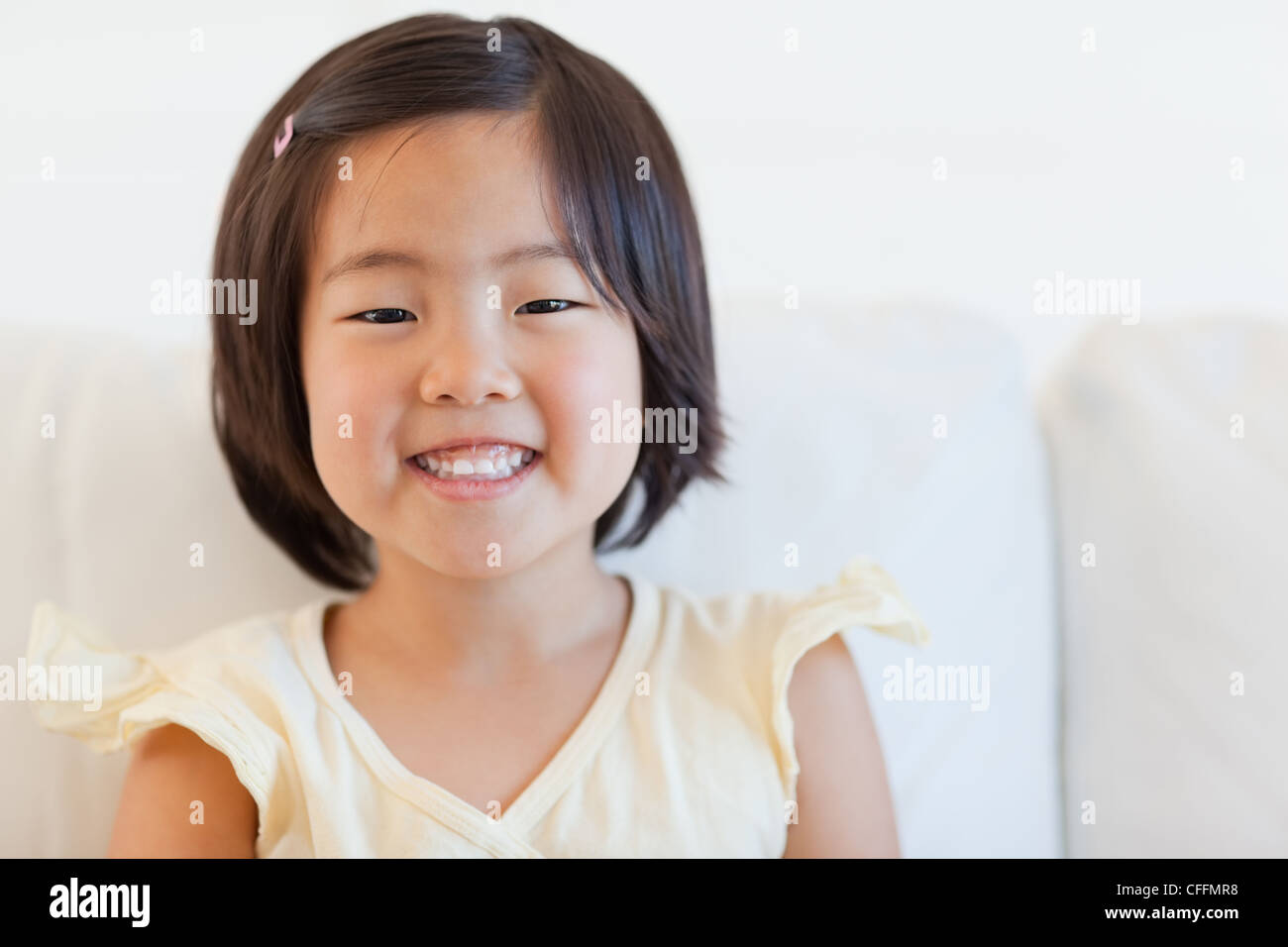 Portrait of a cute young girl smiling as she sits on the couch Stock ...