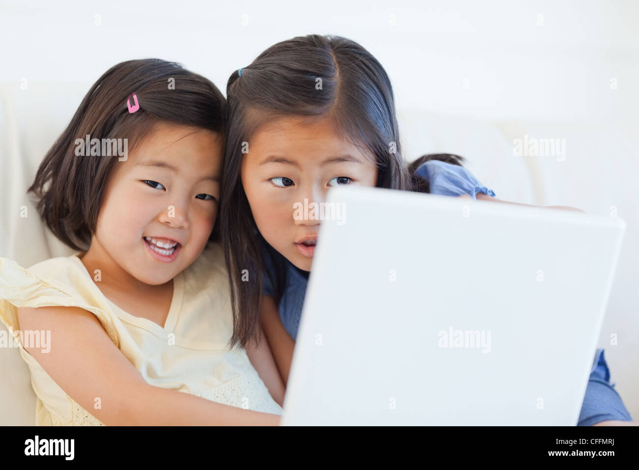 Two girls sitting on the couch while using a tablet Stock Photo - Alamy