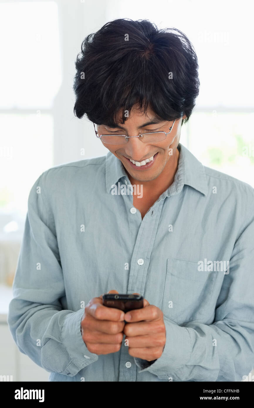 Smiling man looks at his phone as he sends a text Stock Photo