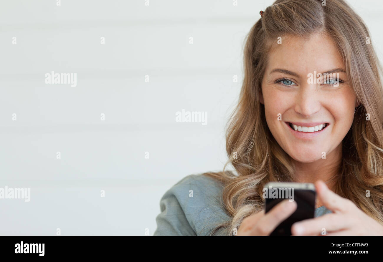 A woman smiling and looking straight ahead as she holds her phone Stock Photo