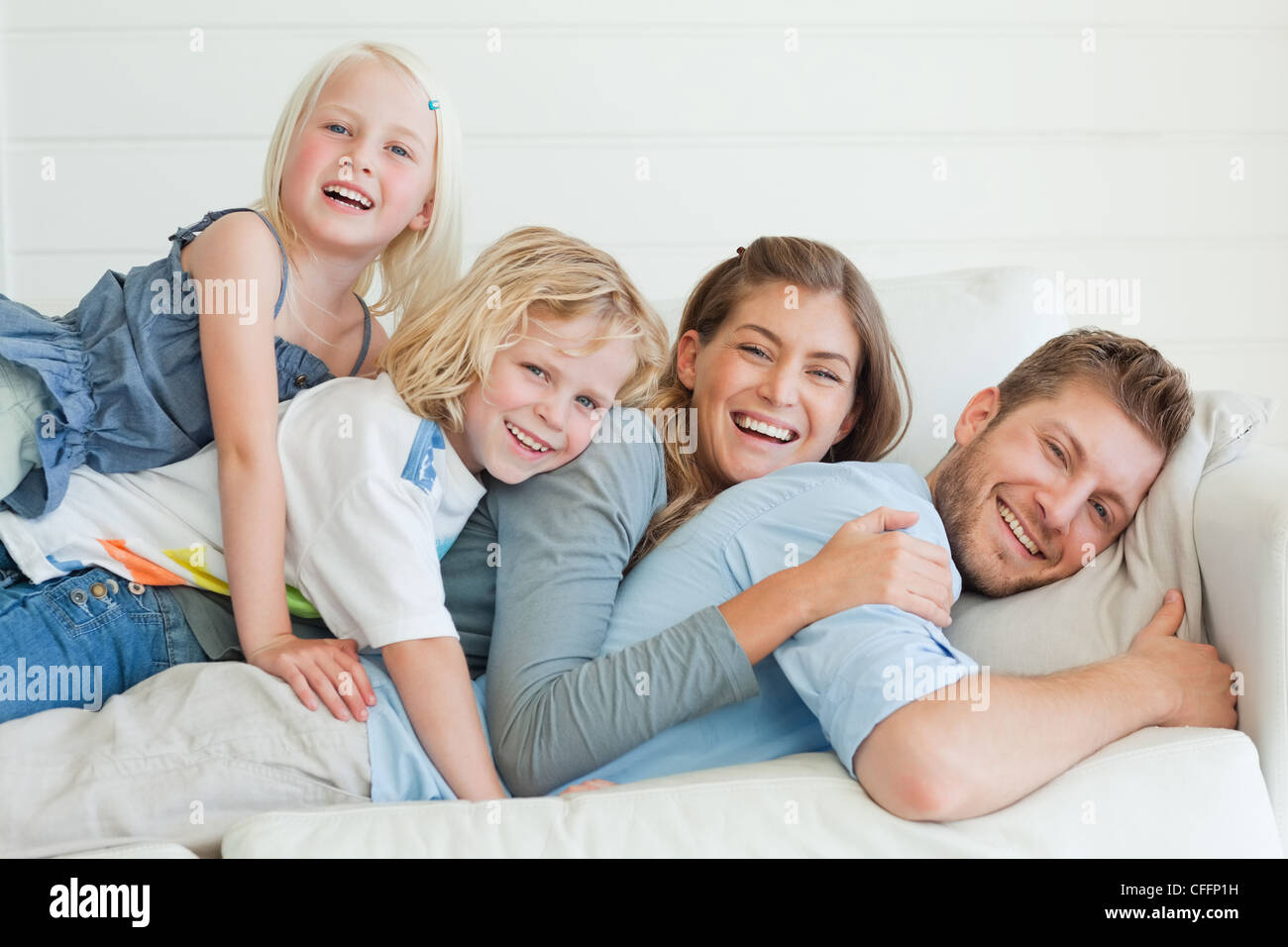 The family all lie on top of each other while lying across the couch