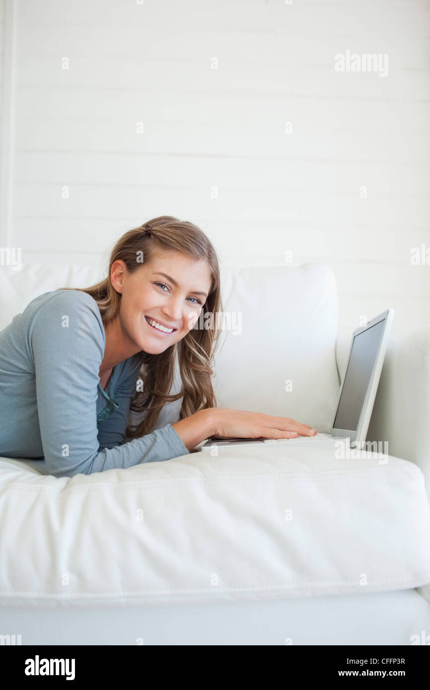 A smiling woman on the couch useing her laptop Stock Photo - Alamy