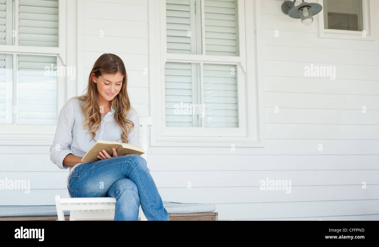 A smiling woman on the porch reading a book Stock Photo - Alamy