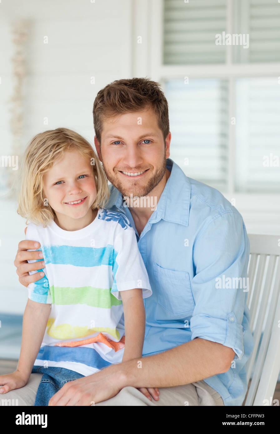 Father and son sit together outside on the seat while smiling Stock ...