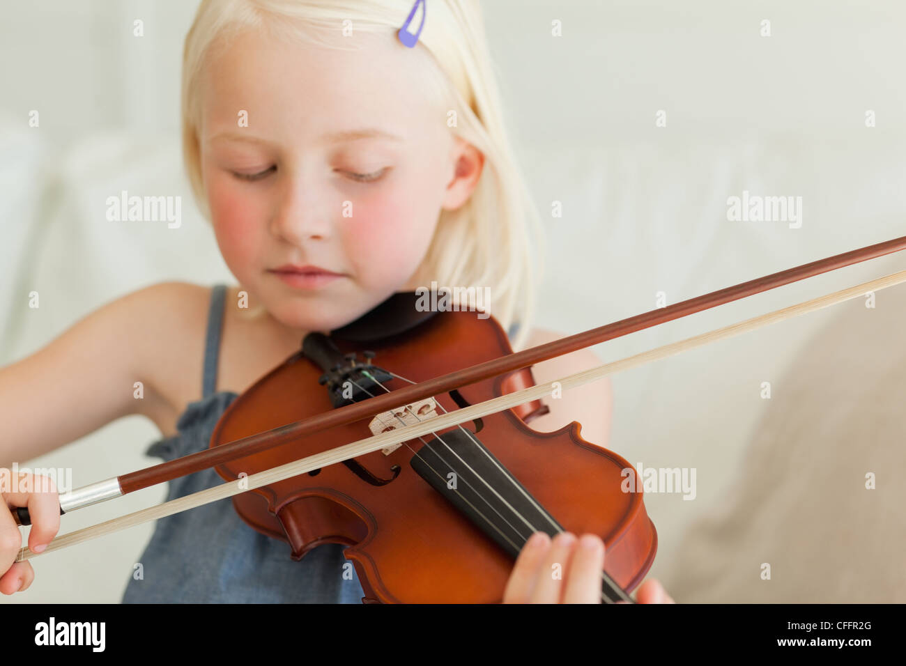 A talented little girl slowly plays the violin Stock Photo