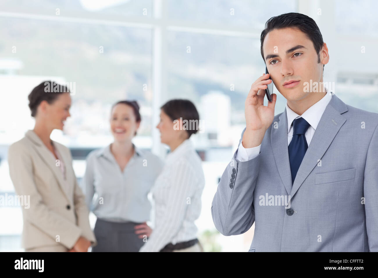 Businessman on his cellphone with colleagues behind him Stock Photo