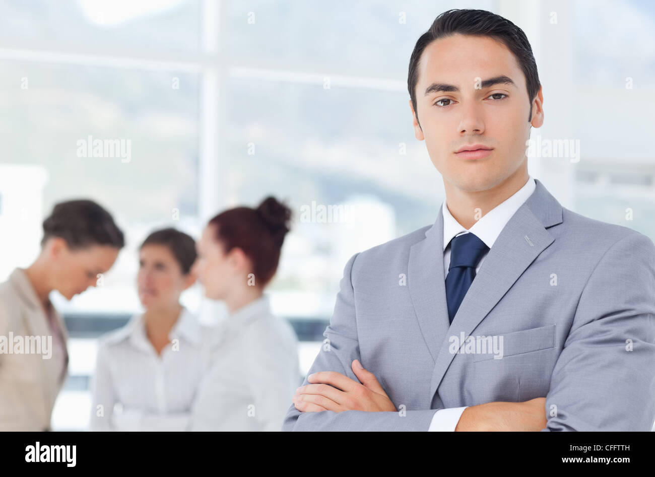 Businessman with arms crossed and colleagues behind him Stock Photo