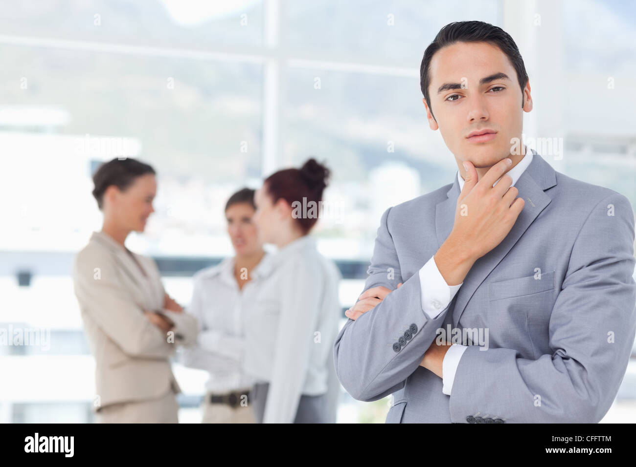 Businessman in thinkers pose and colleagues behind him Stock Photo