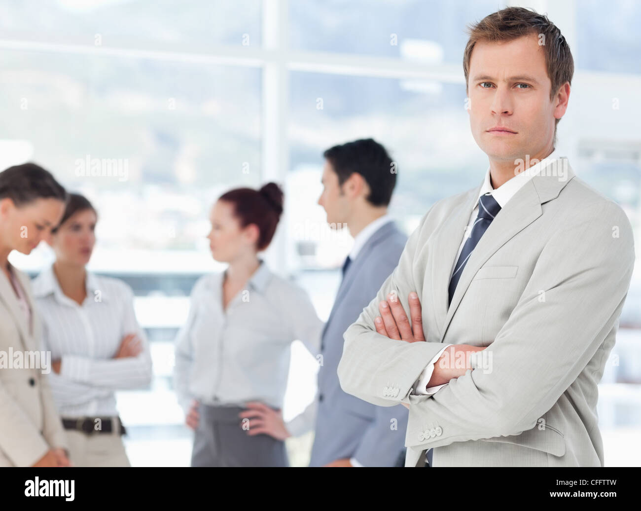 Salesman with arms crossed and colleagues behind him Stock Photo