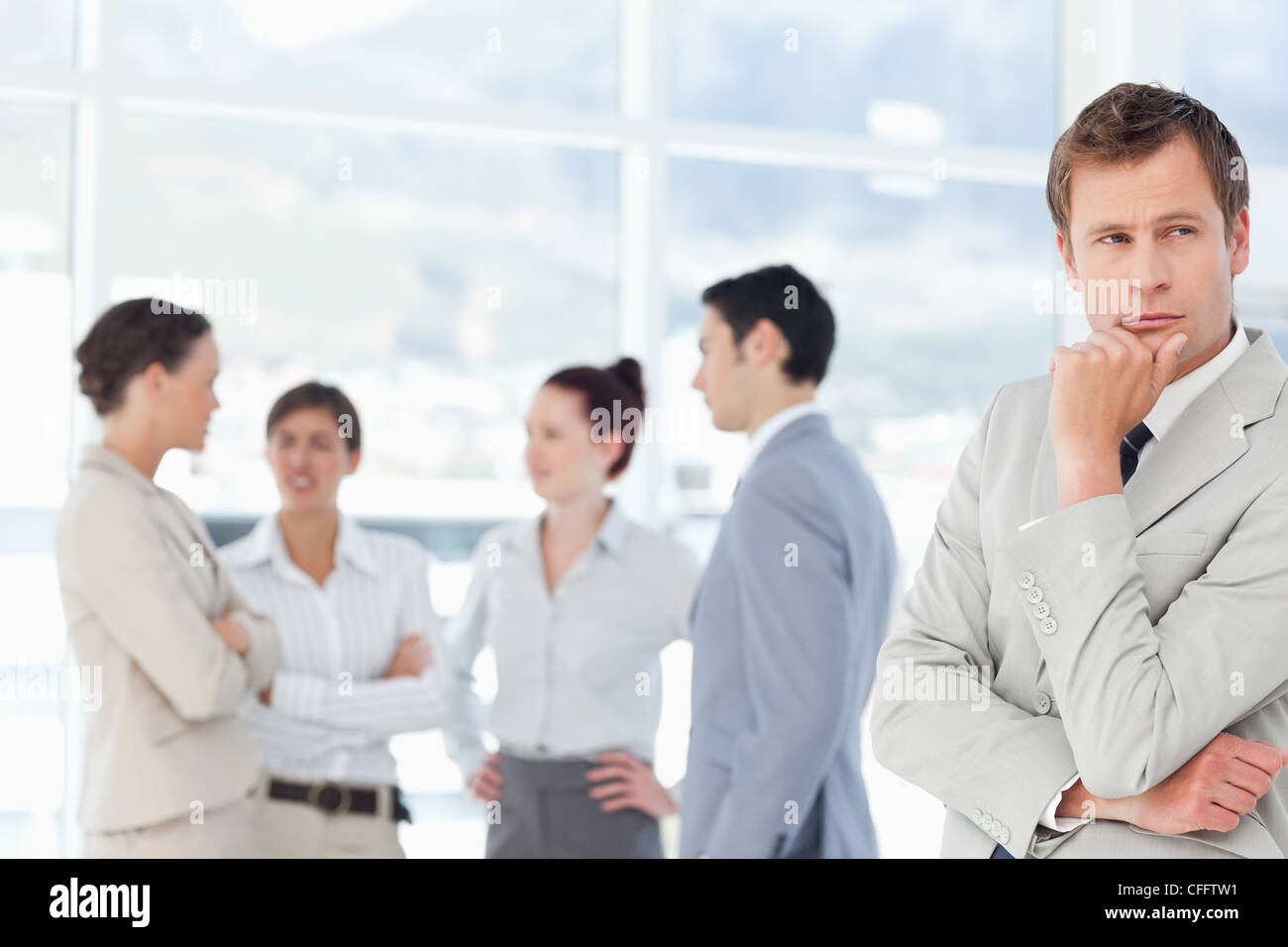 Thoughtful salesman with associates behind him Stock Photo - Alamy