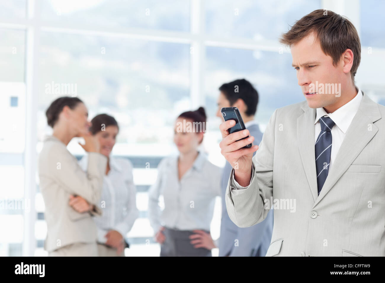 Salesman reading text message with colleagues behind him Stock Photo ...