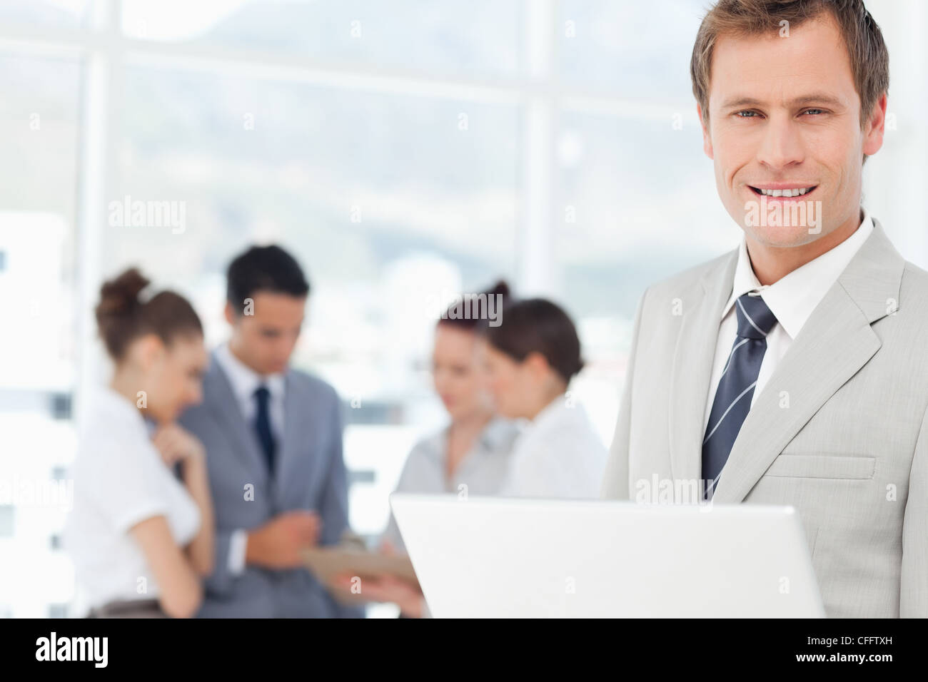 Smiling salesman with notebook and colleagues behind him Stock Photo ...