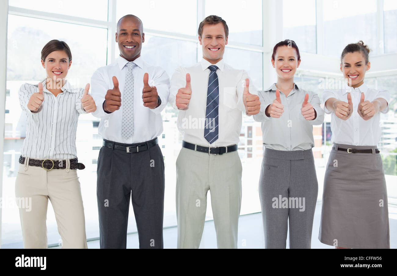 Smiling Business team giving thumbs up Stock Photo - Alamy